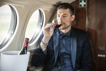 Man drinking wine in a private jet